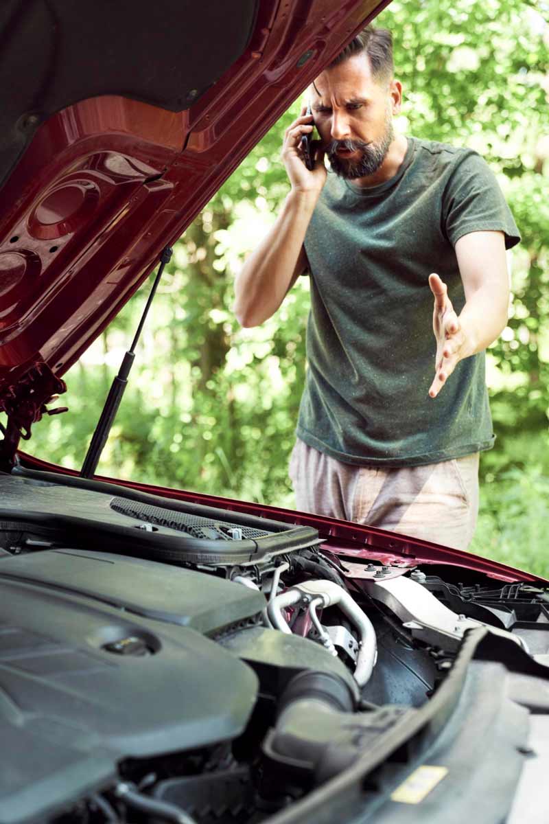 Junger Mann prüft Getriebeschaden bei Schrottauto Ankauf Schwerte